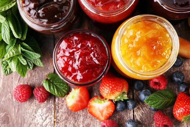 assortment of jams, seasonal berries, plums, mint and fruits.